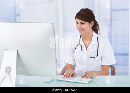Porträt der jungen Ärztin mit Computer am Schreibtisch, in der Klinik Stockfoto