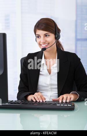 Porträt von überzeugt junge Geschäftsfrau tragen Kopfhörer am Computer-Schreibtisch Stockfoto