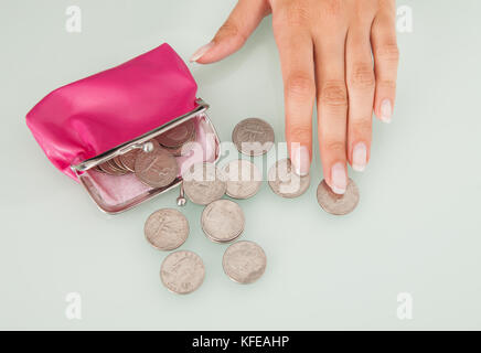 Mittelteil der Geschäftsfrau Münzen zählen verschüttet aus rosa Handtasche am Schreibtisch Stockfoto