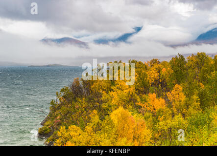 Blick über den See Torneträsk im Herbst, Wolken hängen über den Bergen im Hintergrund und große Wellen auf dem See, Kiruna County, Swedish Lapl Stockfoto