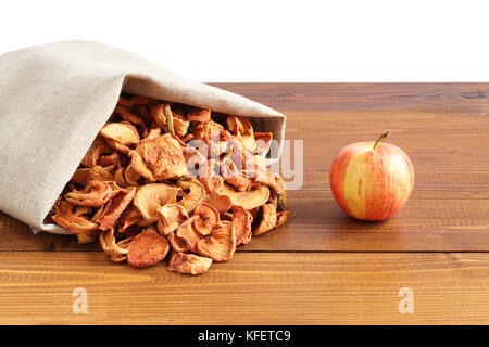 Getrocknete Stücke von Äpfeln in der rauhen Leinen Stoff liegen auf einem Holztisch Stockfoto