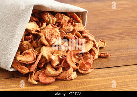 Getrocknete Stücke von Äpfeln in der rauhen Leinen Stoff liegen auf einem Holztisch Stockfoto