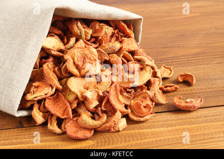 Getrocknete Stücke von Äpfeln in der rauhen Leinen Stoff liegen auf einem Holztisch Stockfoto