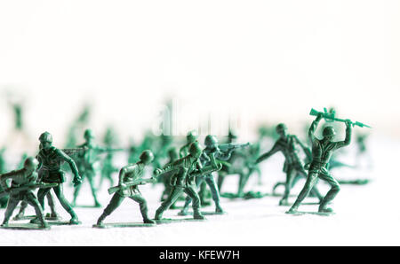 Viele grüne Armee Kunststoff Spielzeug Soldaten auf eine weiße Fläche und Hintergrund organisiert, isoliert, mit Out of Focus plastik Soldaten im Hintergrund Stockfoto