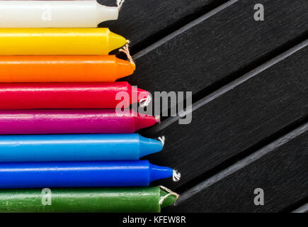 Viele bunte Kerzen in einer einzelnen Zeile und Line, schwarzer Hintergrund, Kerzen der pulsierenden Weiß. Gelb, Orange, Rot und Blau, in einem Regenbogen Farbverlauf Stockfoto