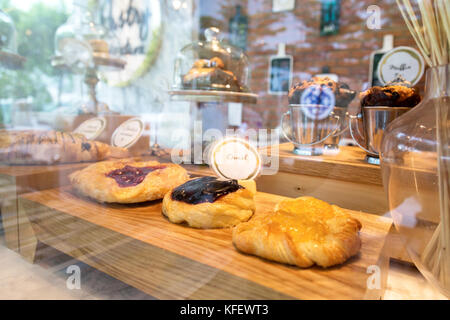 Heidelbeere, Erdbeere und Pfirsich Plundergebäck in Blätterteig Anzeige mit Licht Reflexion auf das Glas an der Bäckerei. Selektive konzentrieren. Stockfoto