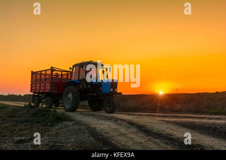 Farm Traktor mit einem Anhänger auf Landstraße Stockfoto