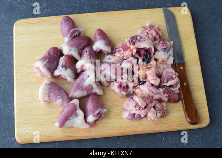 Schritt für Schritt kochen. raw gereinigt Huhn Herz auf einer hölzernen Schneidebrett auf grauem Hintergrund Stockfoto