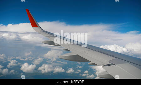 Flügel eines Flugzeugs am Himmel und Wolken auf, Blick aus dem Flugzeug Kabinen Stockfoto