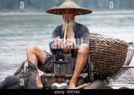 Ein alter Fischer bereitet für den Fischfang auf traditionelle Art und Weise mit Hilfe der Kormoran in Li River in der Nähe von Yangshuo, Xingping, Guangxi, China Stockfoto