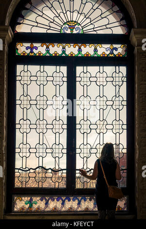 Frau blickt auf das große Dogenpalastfenster zur Brücke von Seufzer in Venedig, Italien Stockfoto