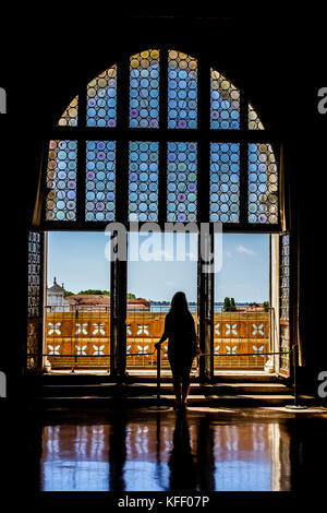 Frau blickt auf das große Dogenpalastfenster zum Canal Grande in Venedig, Italien Stockfoto