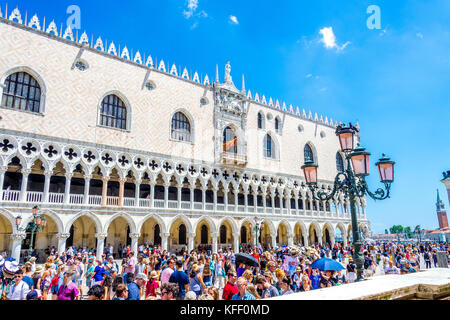 Touristen bewundern die Fassade des Dogenpalastes (Palazzo Ducale), die vom Markusplatz (Piazzetta di San Marco) in Venedig, Italien, aus gesehen wird Stockfoto