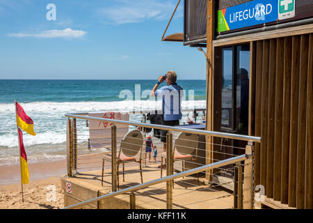 Rettungsschwimmer mit Ferngläsern, um Menschen beim Schwimmen im Meer zu beobachten, in Dee Why, Sydney, Australien, stand im Rettungsschwimmturm Stockfoto