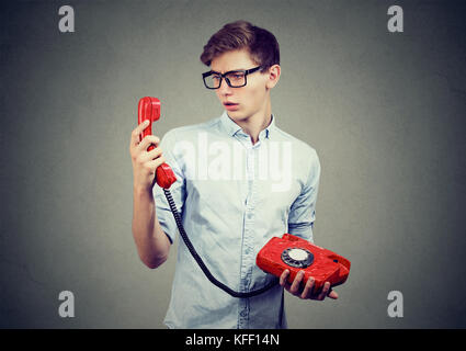 Verwirrt teenager Mann an altmodische Telefon suchen Stockfoto