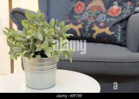 Künstlichen grünen Pflanzen in White Metal Flower Pot in einem Wohnzimmer für Haus und Büro Dekoration ohne Pflege. Stockfoto
