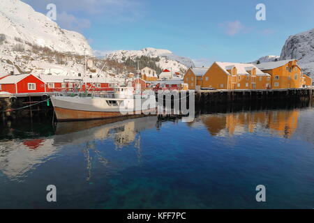 Schnee bedeckt Hafen von nusfjord Fischerdorf - alten hölzernen Fischerboot - rot und orange Fischerhütten oder Rorbuer für touristische Nutzung. stjernhauet - svadet-nes Stockfoto