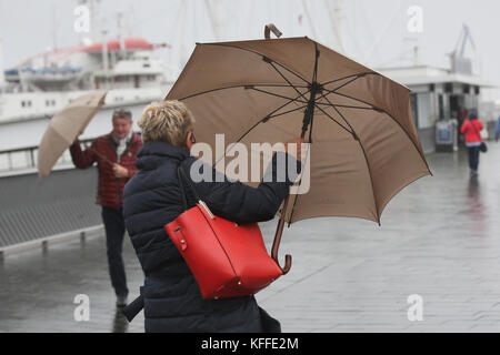 Hamburg, Deutschland. Oktober 2017. Wanderer Klammern sich an einem windigen und regnerischen Tag am 28. Oktober 2017 in Hamburg an ihren Regenschirmen. Der dritte Herbststurm soll später am Abend Hamburg treffen. Der Deutsche Wetterdienst hat gewarnt, dass der Sturm am Sonntag mit voller Wucht zu spüren sein wird. Quelle: Bodo Marks/dpa/Alamy Live News Stockfoto