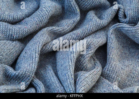 Hintergrund der gestrickt grau Bettwäsche von Ziegenmilch Wolle mit Stricknadeln oder auf eine Strickmaschine in großen Wellen gelegt. Stockfoto