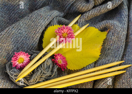 Hintergrund der gestrickt grau Bettwäsche von Ziegenmilch Wolle mit Stricknadeln oder auf eine Strickmaschine in großen Wellen mit hölzernen Stricknadeln gelegt, Ihr Stockfoto