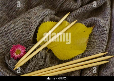 Hintergrund der gestrickt grau Bettwäsche von Ziegenmilch Wolle mit Stricknadeln oder auf eine Strickmaschine in großen Wellen mit hölzernen Stricknadeln gelegt, Ihr Stockfoto