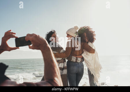 Mann ein Bild von schönen Frauen am Strand entlang. Weibliche Freunde für ein Foto im Freien während ihres Ausflugs posieren. Stockfoto