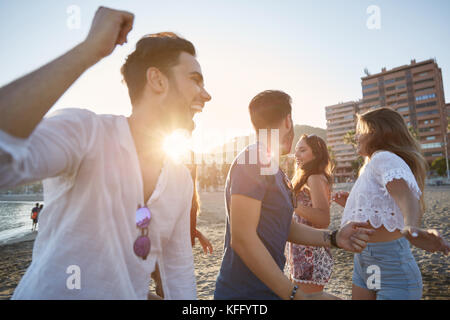 Porträt der jungen Männer tanzen mit Ihren Freundinnen am Strand Stockfoto