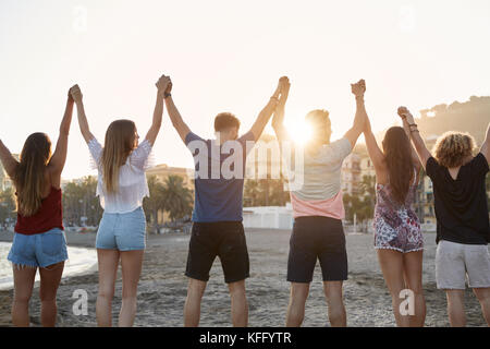 Zurück Portrait von Freunden holding hands up zusammen am Strand Stockfoto