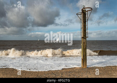 Ausblick aufs Meer vom Strand des Lancashire Hafenstadt Fleetwood mit Wellen, eine hölzerne Pfosten mit einem leichten und Schiffe in der Ferne Stockfoto