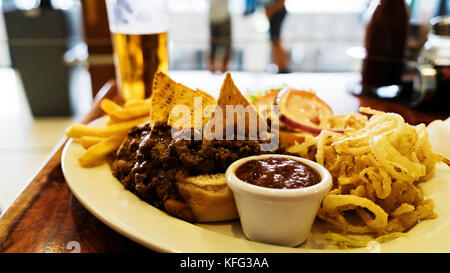 Ungesunde Mahlzeit mit mexikanischen Nacho Chips mit Rindfleisch, Käse, Pommes frites, Zwiebelringe geladen Stockfoto