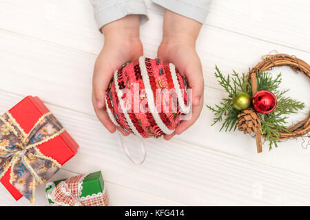 Weihnachten Kalender auf weißem Hintergrund. Child's Hände, die Christmas Ball in der Nähe von geschenkboxen auf weißen Tisch Stockfoto