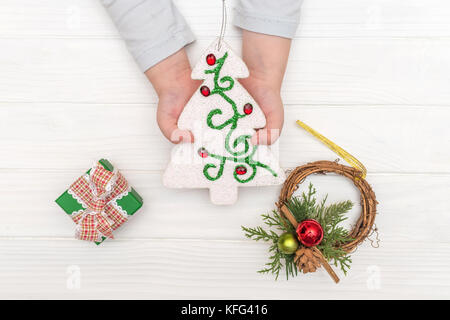 Weihnachten Kalender auf weißem Hintergrund. Child's Hände, die ornamentalen Weihnachtsbaum in der Nähe von geschenkboxen auf weißen Tisch Stockfoto