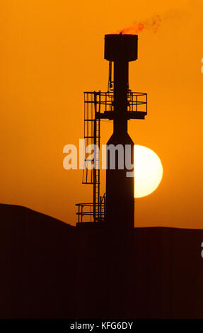 Sonne hinter einem gas Flair der Shaybah Gas öl Luftzerlegungsanlage (gosp), eine große Gas-, Öl- und Produktionsstätte in das Leere Viertel Wüste Saudi Arabiens, in der Nähe der Grenze zu den Vereinigten Arabischen Emiraten. Stockfoto