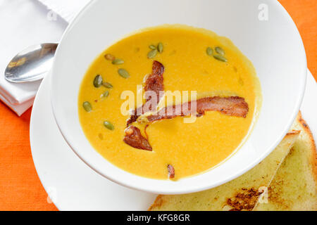 Kürbissuppe mit Speck garniert mit rostigen Brot Stockfoto