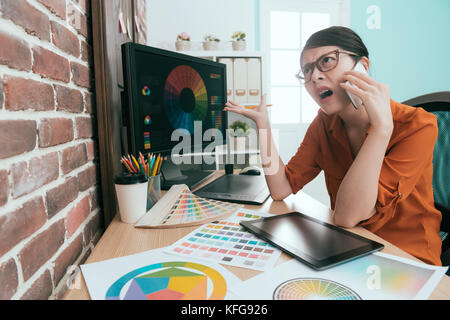 Junge schöne Grafik Designerin Frau mit Mobiltelefon im Gespräch mit Kunden diskutieren Design planen und Probleme verärgert. Stockfoto