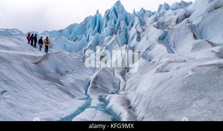 Führt eine Gruppe von bunt gekleideten Touristen auf eine kurze Gletscherwanderung mit blauem Himmel, Landschaften, Flüsse und Gletscher Gipfel Stockfoto