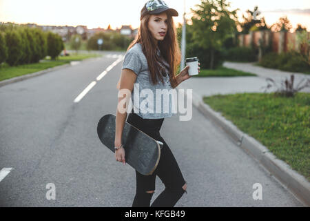 Skater Mädchen mit kaffeetasse vor der Sonne beginnt Ihr Tag. Stockfoto