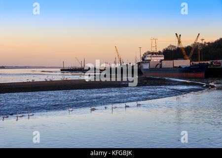 Sonnenuntergang am Mistley Kai am Fluss Stour, Großbritannien, mit Schiffen angedockt und Schwäne entlang des Flusses voran Stockfoto