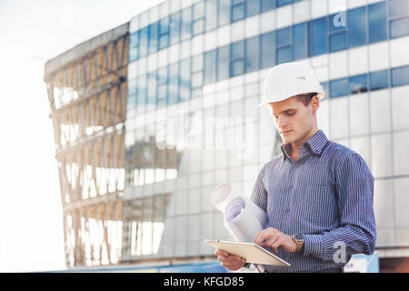 Portrait von selbstbewussten jungen Architekten oder Chief Engineer verwendet digitale Tablet auf der Baustelle Stockfoto