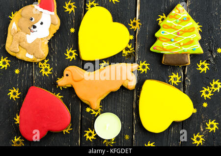 Eine Vielzahl von Cookies in der Form eines Hundes. Fest von einem gelben Hund. Der dunkle Hintergrund. Stockfoto