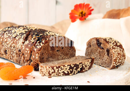 Brotlaib aus Roggen ungesäuertes Brot ohne Hefe mit getrockneten Aprikosen und Rosinen bestreuten Samen von Flachs und Sesam Stockfoto