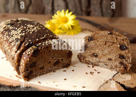 Laib und Roggenscheiben ungesäuertes Brot ohne Hefe mit getrockneten Aprikosen und Rosinen gesprinklerten Samen von Flachs und Sesam Stockfoto