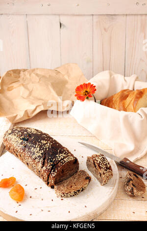 Laib und Roggenscheiben ungesäuertes Brot ohne Hefe mit getrockneten Aprikosen und Rosinen gesprinklerten Samen von Flachs und Sesam Stockfoto