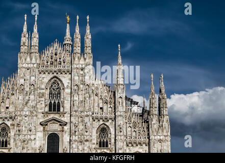 Ein Blick auf den Mailänder Dom Fassade mit einem blauen Himmel im Hintergrund und einer großen Wolke in der Nähe von Gebäude Stockfoto