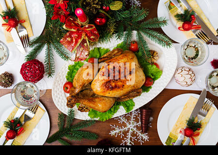 Gebackener Truthahn oder Hähnchen. Weihnachten Tabelle einen Truthahn serviert wird, mit hellen Lametta und Kerzen dekoriert. Fried Chicken, Tisch. Weihnachtsessen Stockfoto