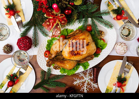 Gebackener Truthahn oder Hähnchen. Weihnachten Tabelle einen Truthahn serviert wird, mit hellen Lametta und Kerzen dekoriert. Fried Chicken, Tisch. Weihnachtsessen Stockfoto