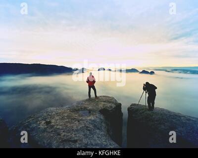Silhouetten der Mann Fotografen. Männer auf Berg. Peak mit zwei Männern, die Fotos im Herbst Sonnenaufgang Stockfoto