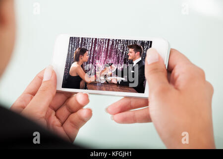 Bild der Geschäftsfrau beobachten paar Toasten Weingläser auf Handy über weißem Hintergrund abgeschnitten Stockfoto