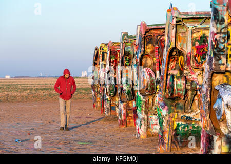 Amarillo, Texas, USA. 18. Oktober 2015. Nach Mann, der eine Haube Spaziergänge an der Seite des alten begraben Fahrzeuge bei Cadillac Ranch in den frühen Morgenstunden. Stockfoto