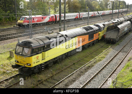 Virgin trainiert die E-Lokomotiven der Baureihe 91 der East Coast, vorbei an den Colas Rail Freight Lokomotiven 70814 und 60095 auf den Anschlussgleisen von Holgate südlich des Bahnhofs York, Großbritannien. Stockfoto